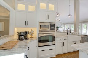 A modern kitchen with white cabinetry, stainless steel appliances, and a marble countertop. - Golf Course View: Elegant Hot Springs Village Home (Hot Springs Village)