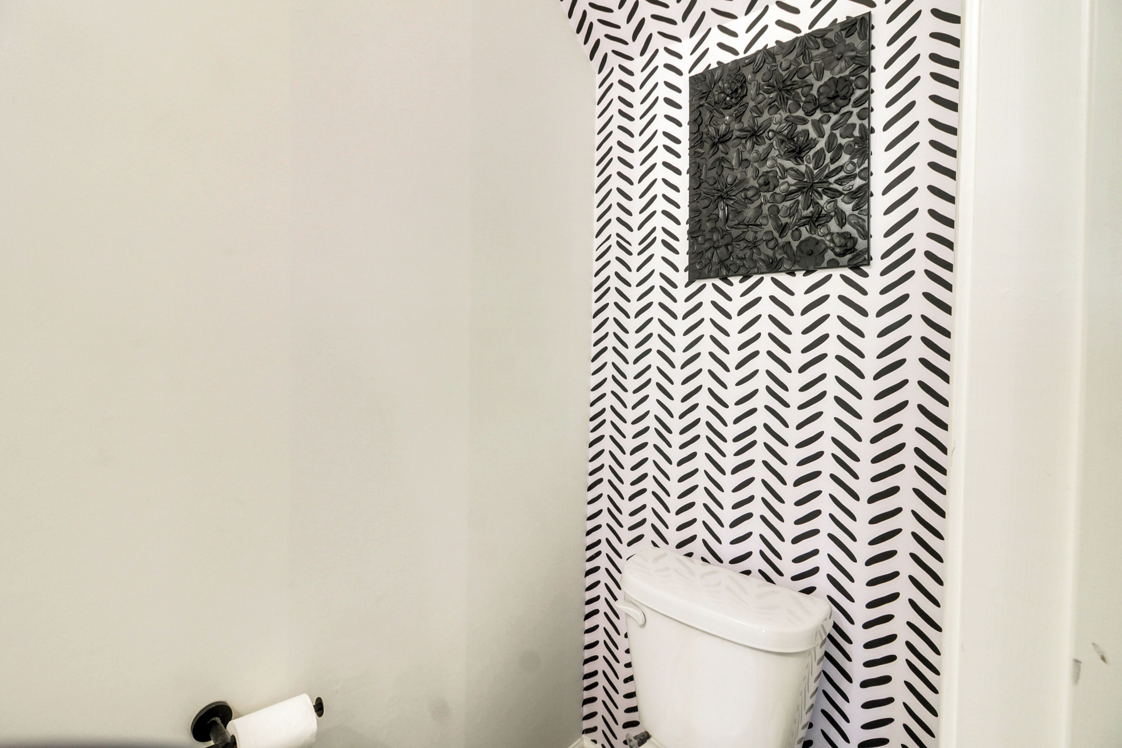 A bathroom with a white toilet, a towel dispenser, and a patterned wall.