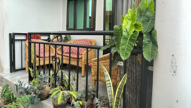 A balcony with wicker furniture, potted plants, and a view of the street. - Cool 1-bedroom with a balcony in vibrant Kigali (Kigali)