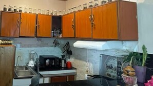 A kitchen with wooden cabinets, a black countertop, and a sink. - Cool 1-bedroom with a balcony in vibrant Kigali (Kigali)