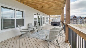 A wooden deck with Adirondack chairs, a table, and a grill area.