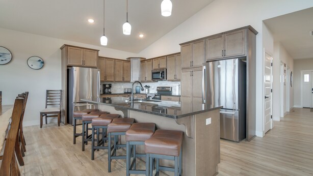 A modern kitchen with stainless steel appliances, wooden cabinets, and a central island with bar stools.