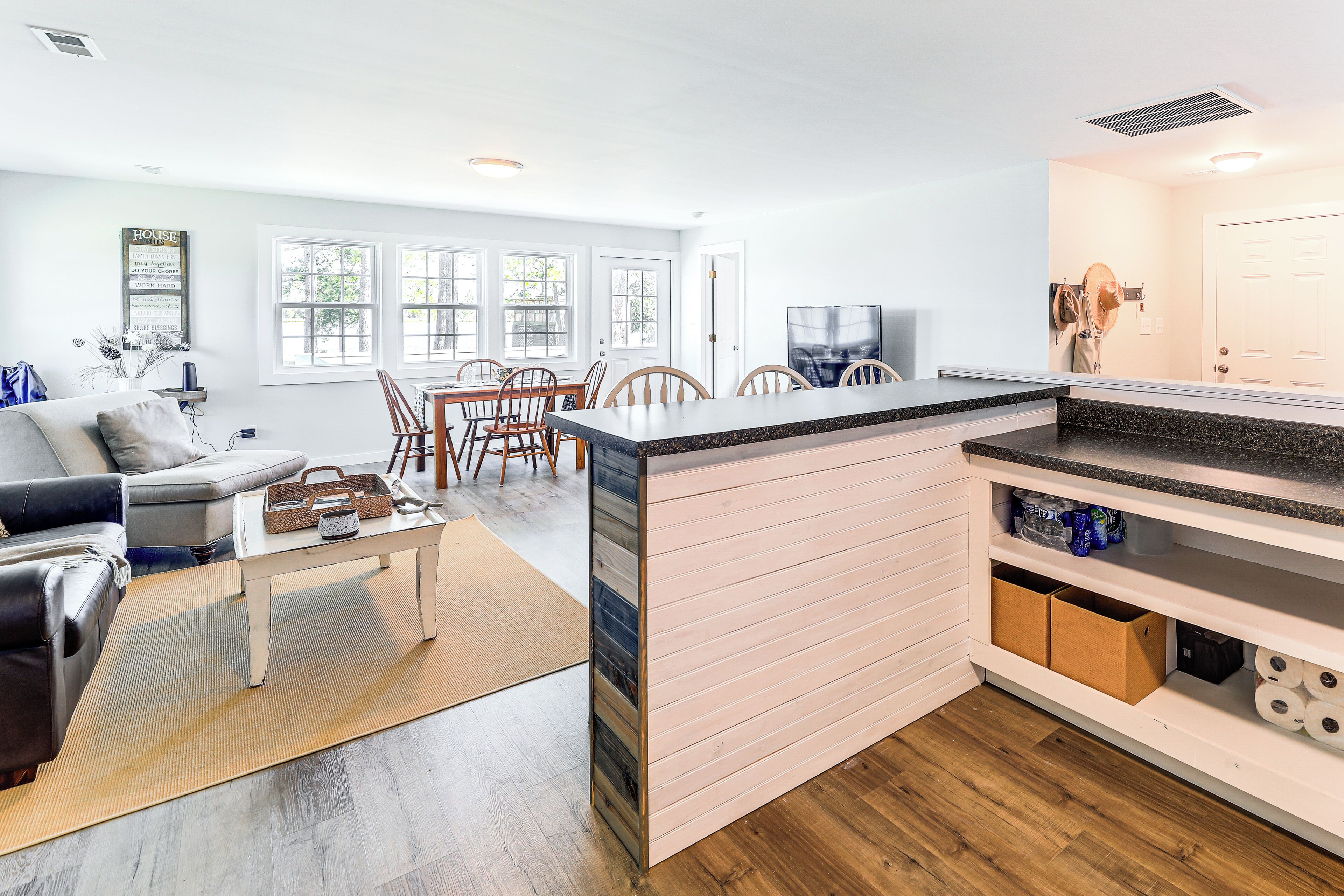 A modern kitchen with a central island, wooden flooring, and a dining area with chairs and a table.