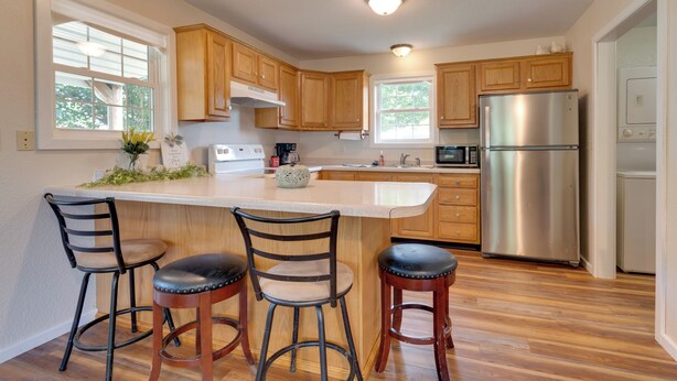 A kitchen with wooden cabinets, a stainless steel refrigerator, a microwave, and a large island with bar stools. - 16 Mi to Lake Sara Beach - Pet-friendly Home (Montrose)
