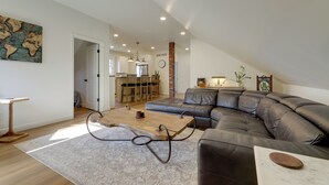 A spacious living area with a large sectional sofa, a wooden coffee table, and a dining area in the background. - 1 Block to Loveland Bike Trail: 'the Frog Man Inn' (Loveland)