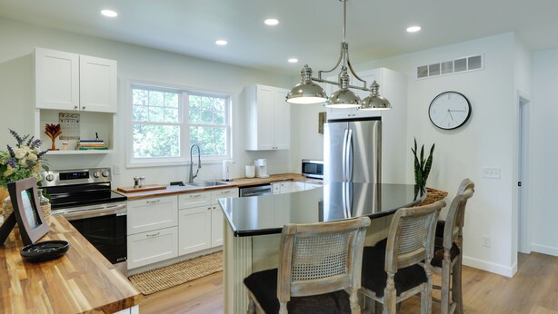 A modern kitchen with white cabinetry, stainless steel appliances, a large island with bar stools, and a chandelier. - 1 Block to Loveland Bike Trail: 'the Frog Man Inn' (Loveland)