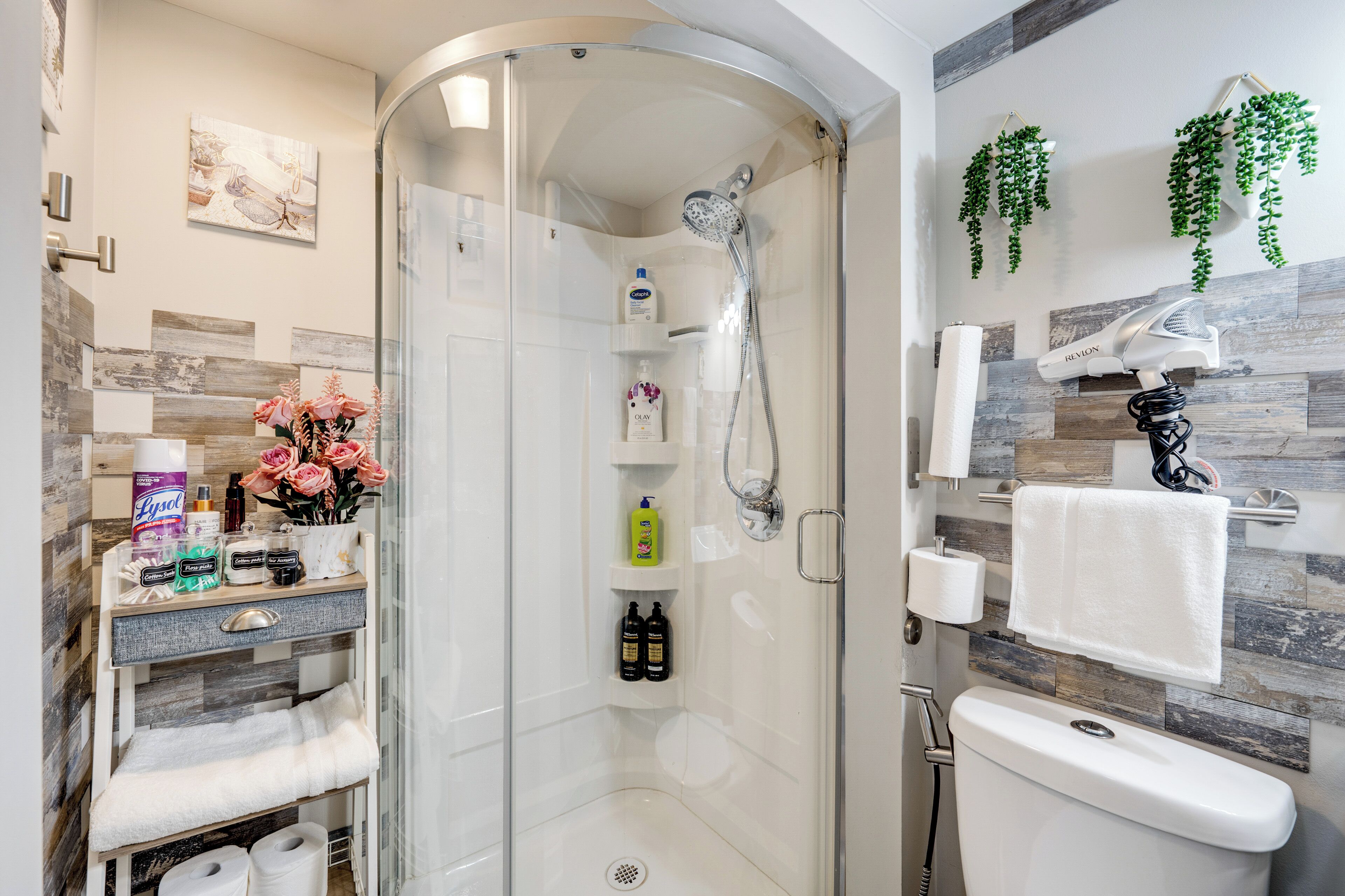 A modern bathroom with a glass-enclosed shower, a vanity with toiletries, and a towel rack.