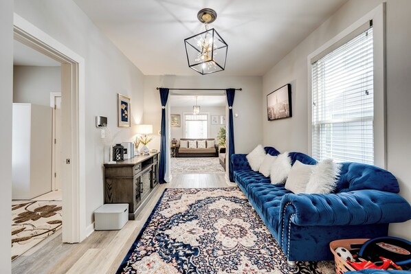 A hallway with a blue sofa, a patterned rug, and a chandelier. - 1 Mi to Dtwn Elgin: Dutch Colonial w/ Lovely Patio (Elgin)