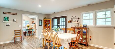 A dining area with a table set for four, surrounded by wooden chairs, and a kitchen visible through an open doorway.
