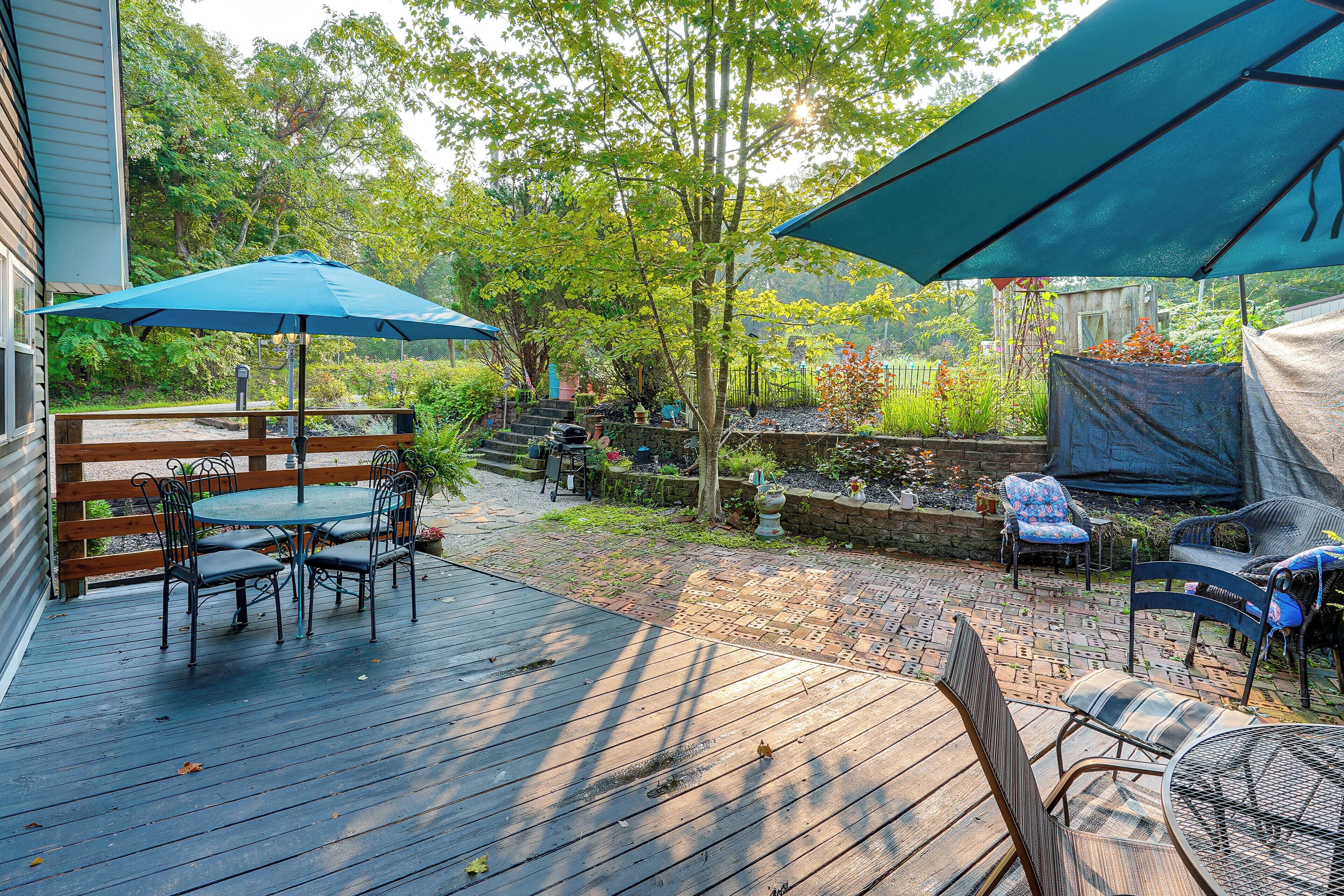 A wooden deck with outdoor furniture, including a table and chairs, under large umbrellas.