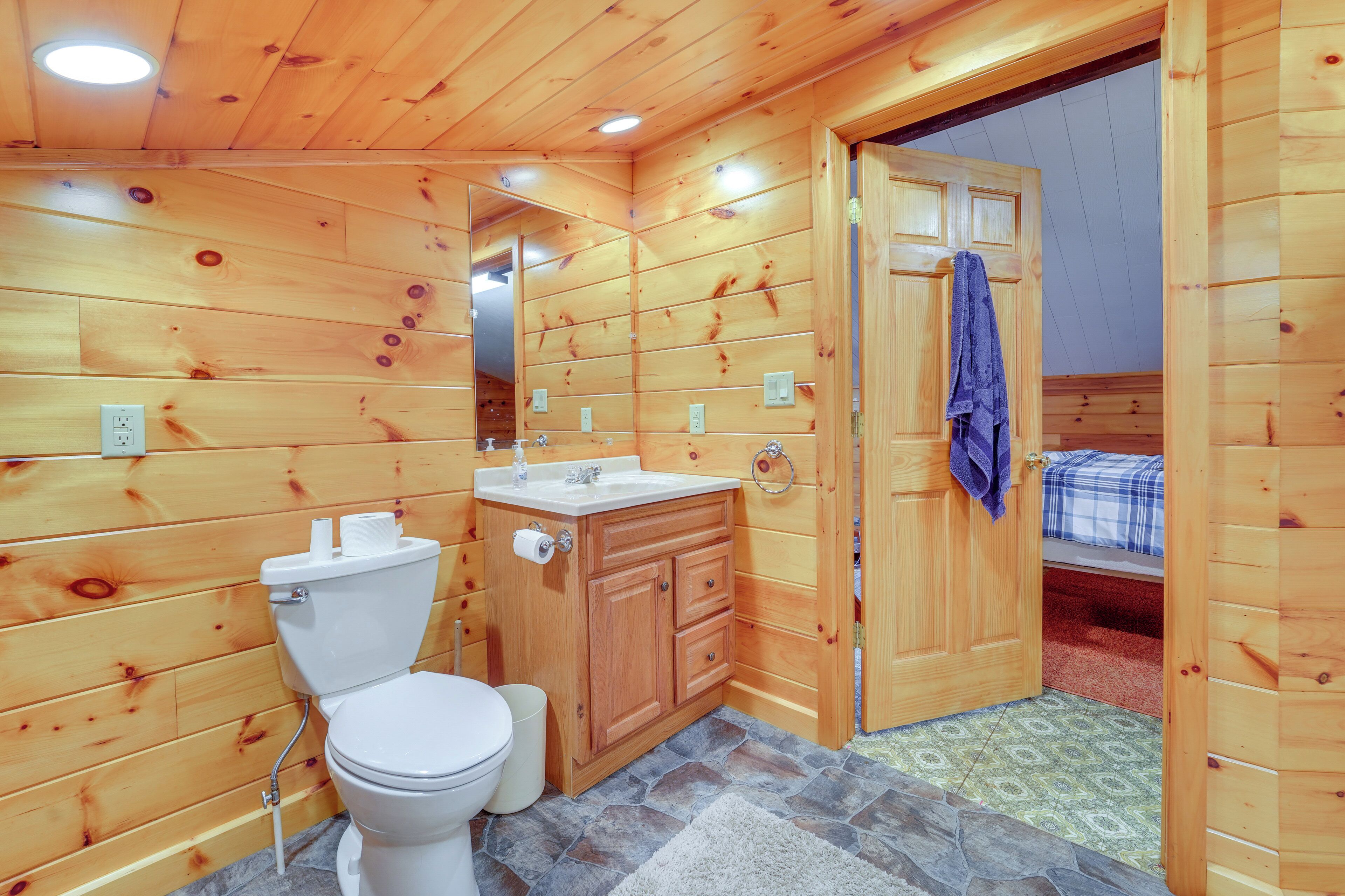 Ein Badezimmer einer Holzhütte mit Toilette, Waschbecken und Schrank.