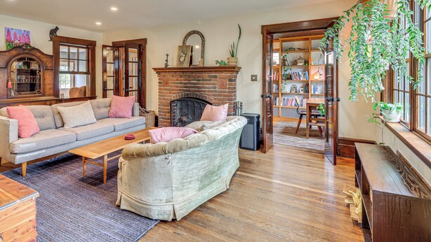 Una sala de estar con chimenea, un sofá, una mesa de centro y una estantería.