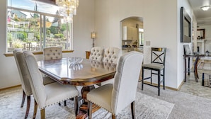 Ein Esszimmer mit einem großen Holztisch, gepolsterten Stühlen und einer Chandelier.
