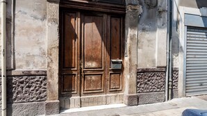 Une grande porte en bois, avec une boîte aux lettres sur le côté droit, intégrée dans un bâtiment aux murs en pierre et en béton.
