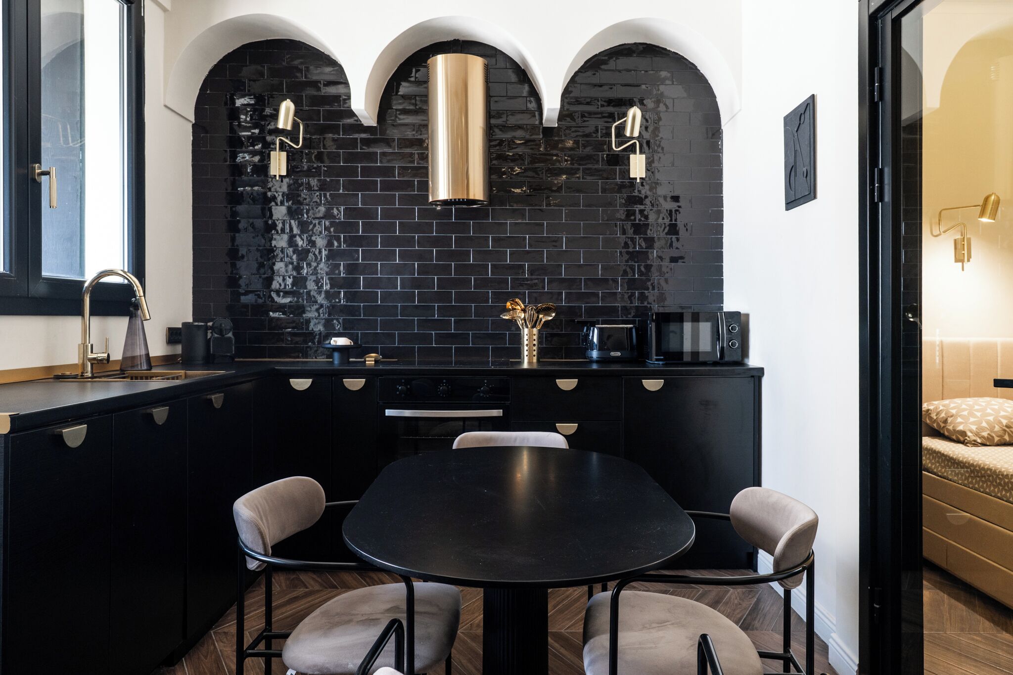 A modern kitchen with black cabinetry, a black dining table, and a black backsplash.