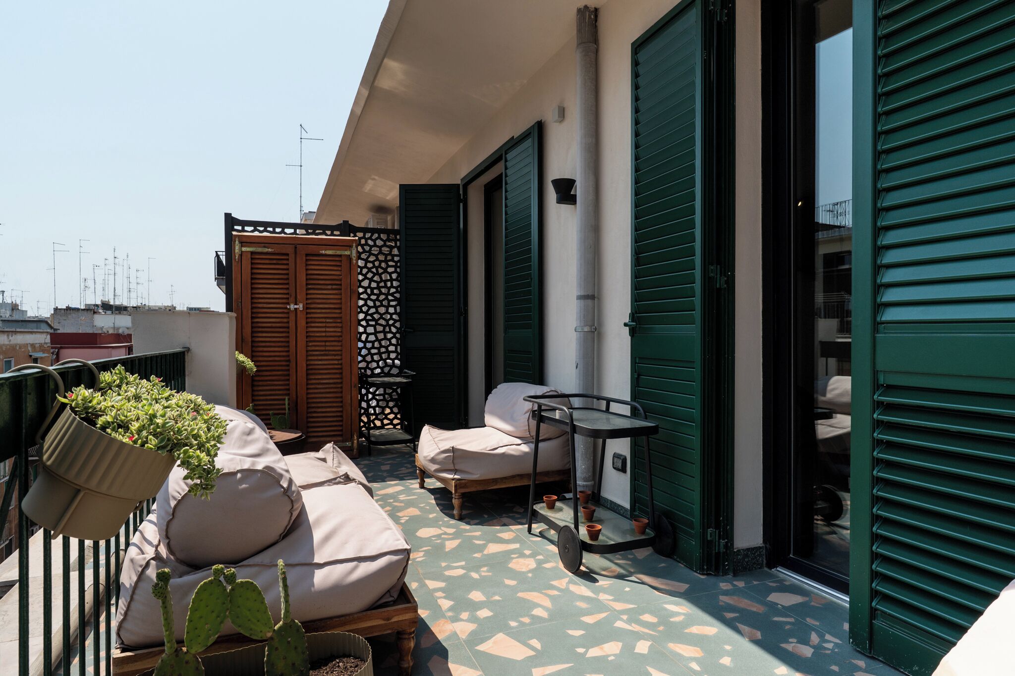 A balcony with a sofa, a table, and potted plants.