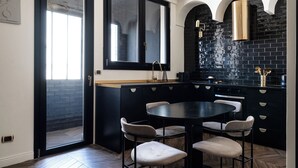 Une cuisine moderne aux couleurs noir et blanc, comprenant une table de salle à manger ronde avec quatre chaises, un plan de travail noir et une fenêtre au-dessus de l’évier.
