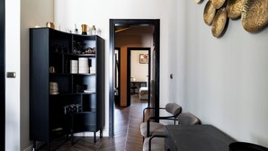 Une cuisine moderne avec un plancher en bois foncé, un meuble noir contenant de la verrerie, et un coin repas avec une table et des chaises en marbre.