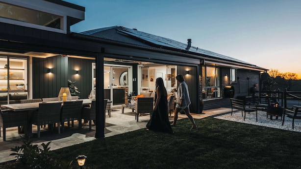 Una casa moderna con patio, mobiliario exterior e ingreso bien iluminado.