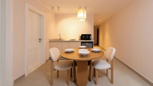 A dining area with a round wooden table, four chairs, and a hanging light fixture. - Kennah Chill & Swim | 2BR with Pool, October City (6th of October City)