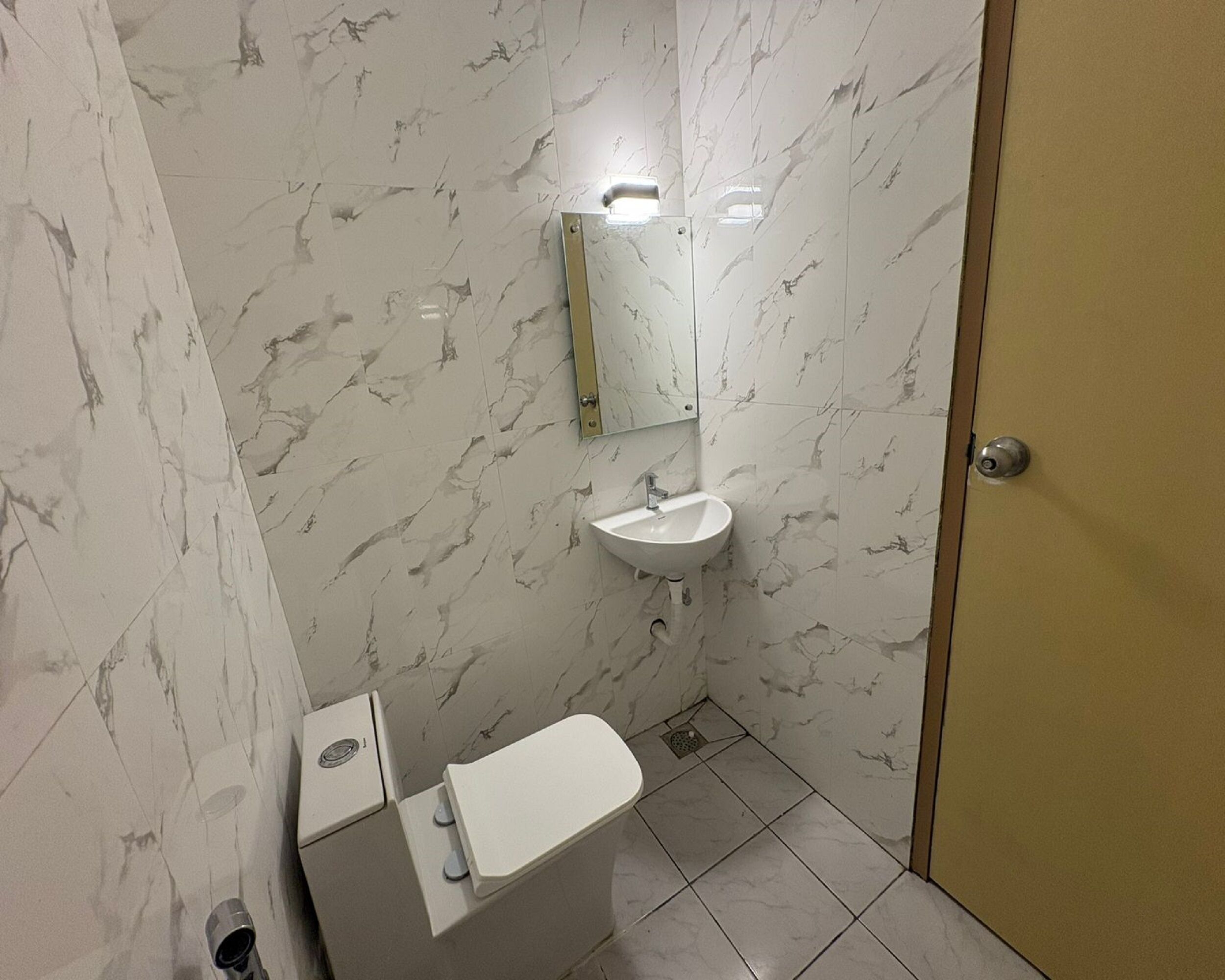 A bathroom with a toilet, sink, and mirror.