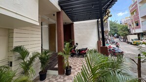 A covered outdoor area with potted plants, a motorcycle, and a parked truck.