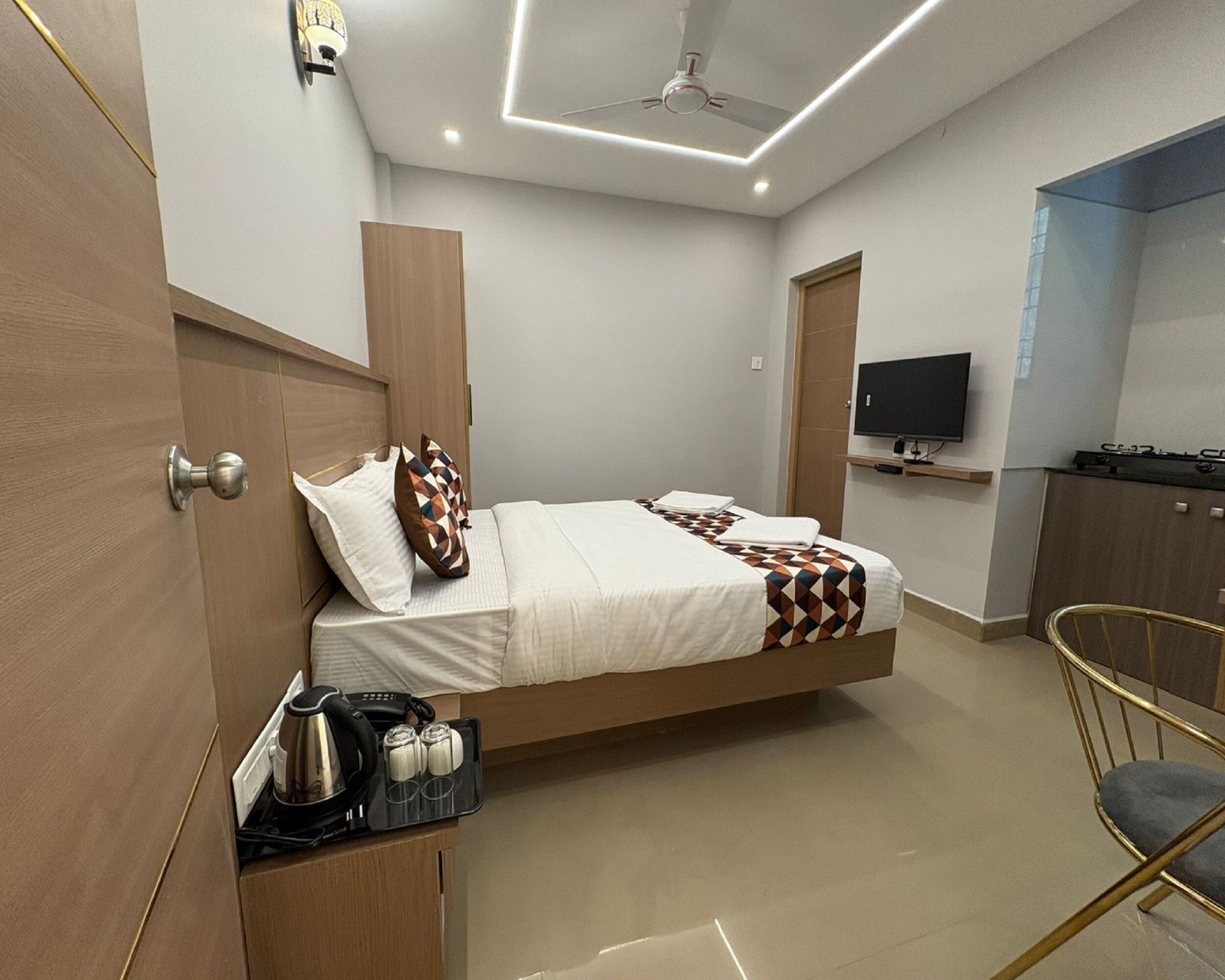A modern bedroom with a bed, bedside table, and a TV on the wall.
