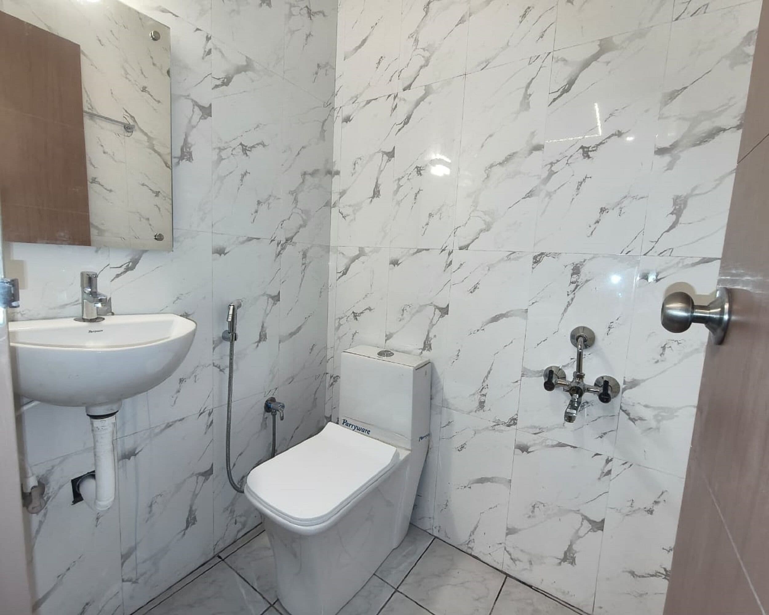 A bathroom with a white sink, a toilet, and a shower with a wall-mounted faucet.