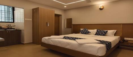 Habitación de hotel moderna con una cama grande, ventilador de techo y vistas a la ciudad por la ventana.
