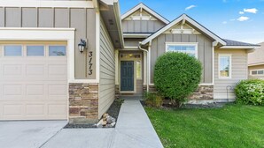 Une maison à deux étages, avec des fondations en pierre, un garage et une pelouse bien entretenue.