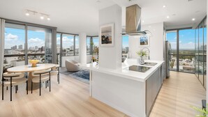 Een moderne keuken met een centraal eiland, grote ramen en uitzicht op de stad.