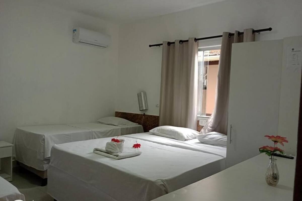 Habitación de hotel con dos camas, una mesita, una silla, un espejo y una ventana con cortinas.