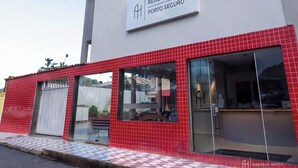 Un hotel con fachada de tejas rojas, un letrero que dice 'REDE ANDRADE PORTO SEGURO' y ventanas grandes.