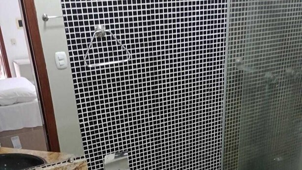 Un baño con inodoro negro, lavamanos con encimera de mármol y un cubo de basura.