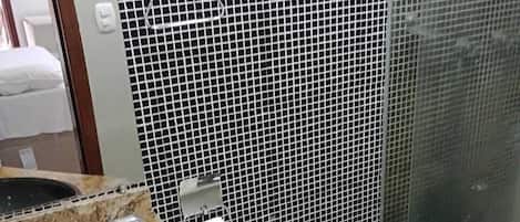 Un baño con inodoro negro, lavamanos con encimera de mármol y un cubo de basura.