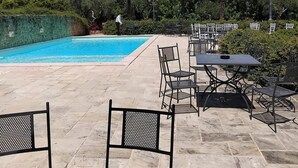 Un área junto a la piscina con sillones de descanso y mesas.