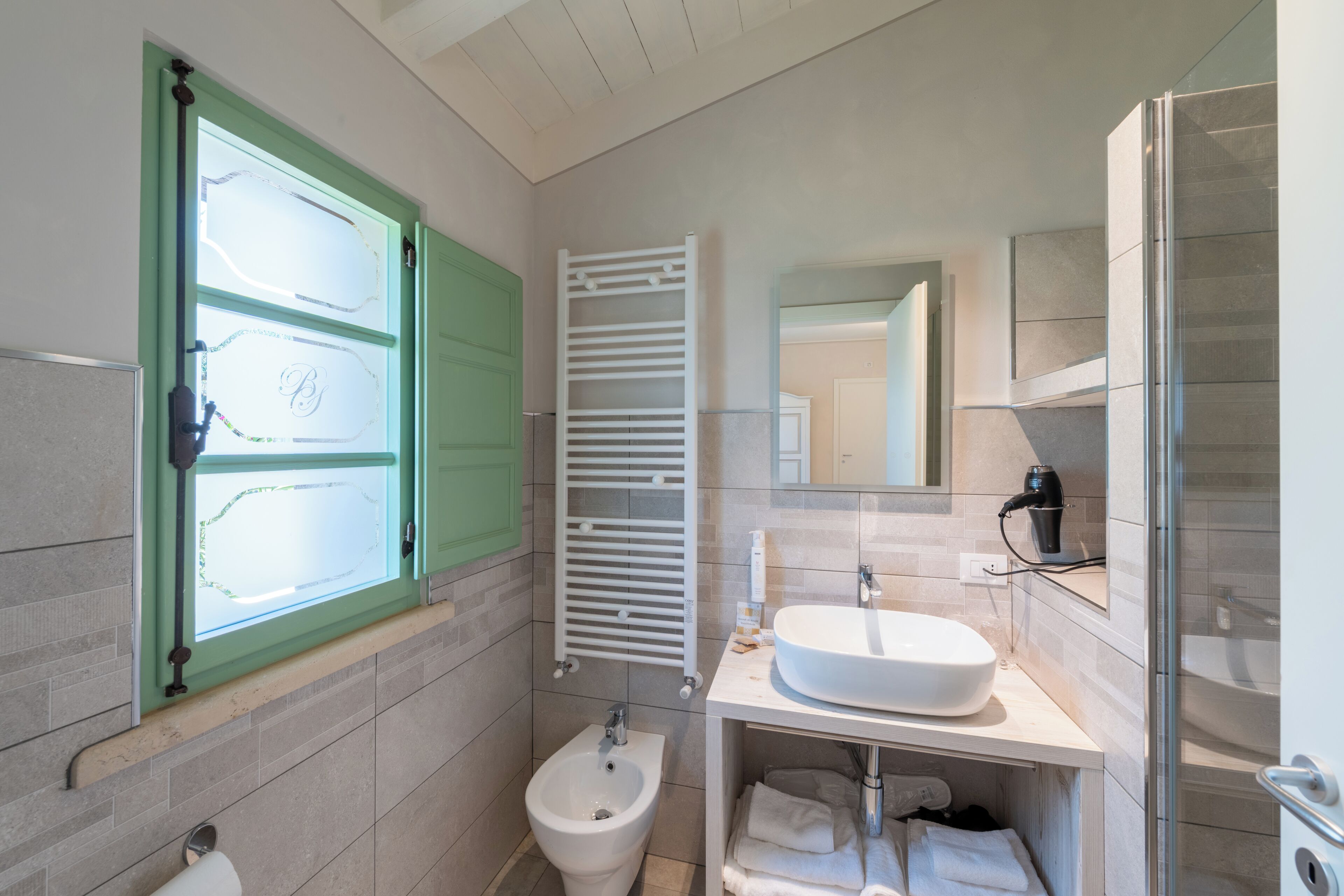 A modern bathroom with a bidet, a sink, a mirror, and a towel rack.