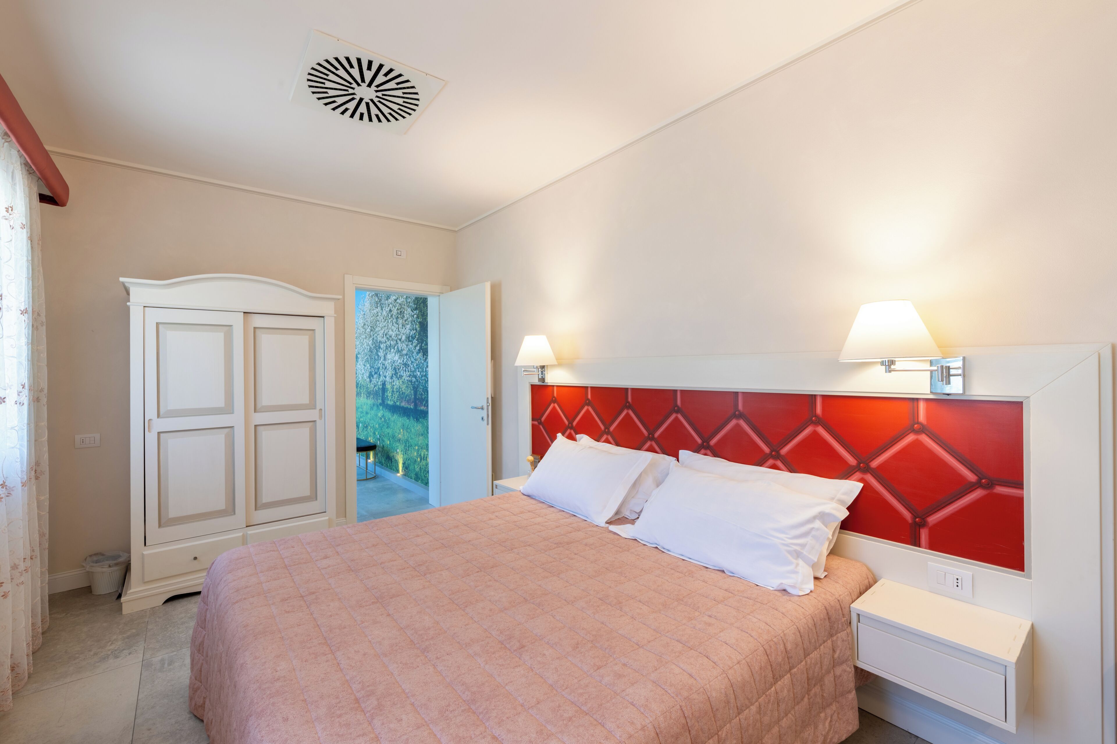 Une chambre à coucher avec un lit, des tables de chevet, une armoire et une tête de lit rouge.