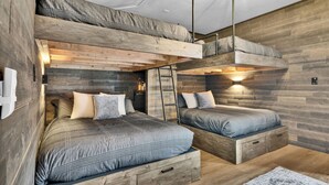 A bedroom with two bunk beds, wooden walls, and a mirror. - Game Room + Bar + Lake Views | Gated Marina + Mini Golf | Naci Lakeview Retreat (Bradley)