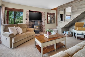 A living room with a brick fireplace, a flat-screen TV, a sofa, and a coffee table.