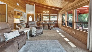 A cozy cabin interior with a wooden ceiling, a dining area, and large windows offering a view of the outdoors. - Game Room + Bar + Lake Views | Gated Marina + Mini Golf | Naci Lakeview Retreat (Bradley)