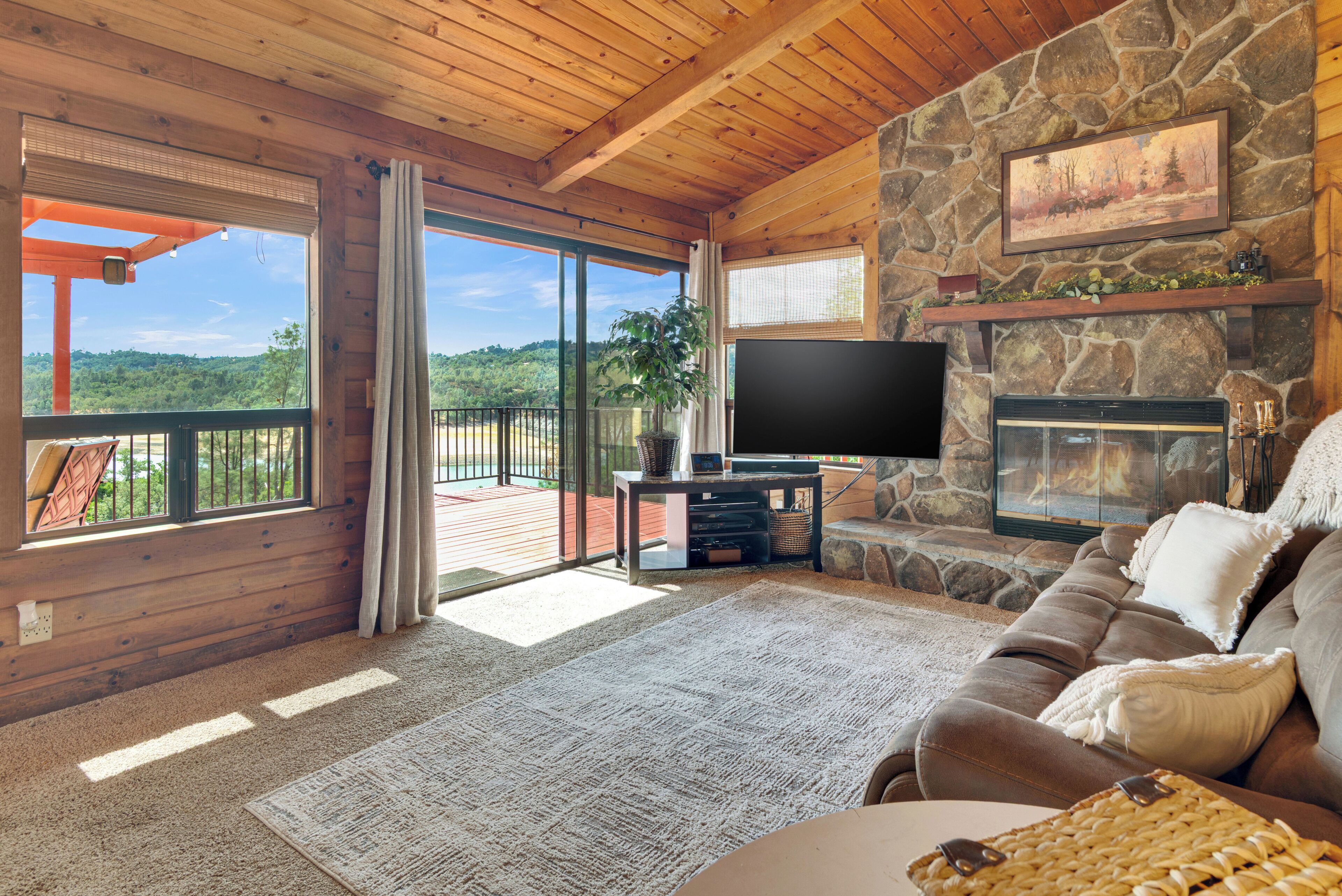 A cozy living room with a stone fireplace, a flat-screen TV, and a comfortable sofa.