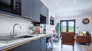 A modern kitchen with a built-in oven, a sink, and a dining area with a brown sofa and a table.