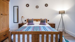 A bedroom with a wooden bed, a nightstand, a lamp, and a wardrobe.