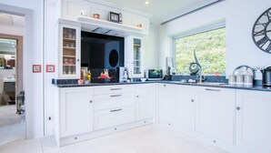 A modern kitchen with white cabinetry, a built-in microwave, and a large window providing a view of greenery.