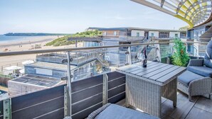 A balcony with a view of the beach and a building with a modern design.