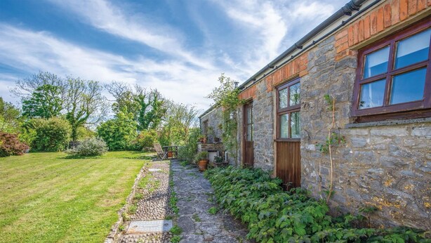 A stone building with a wooden door and windows, a stone pathway, and a well-maintained lawn. - Haggard - 3 Bedroom Cottage - Manorbier (Tenby)