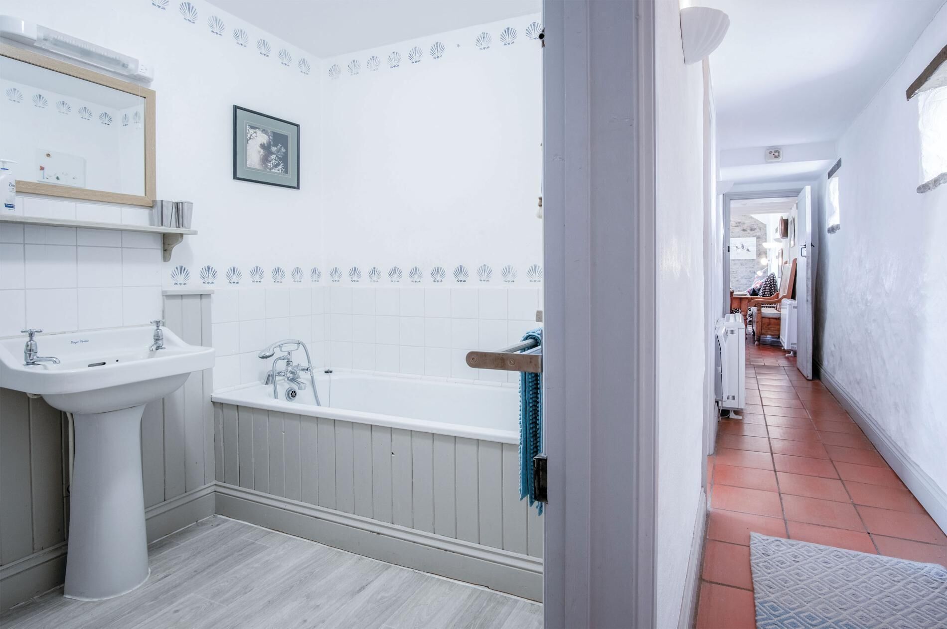 A bathroom with a sink, bathtub, and a framed picture on the wall.