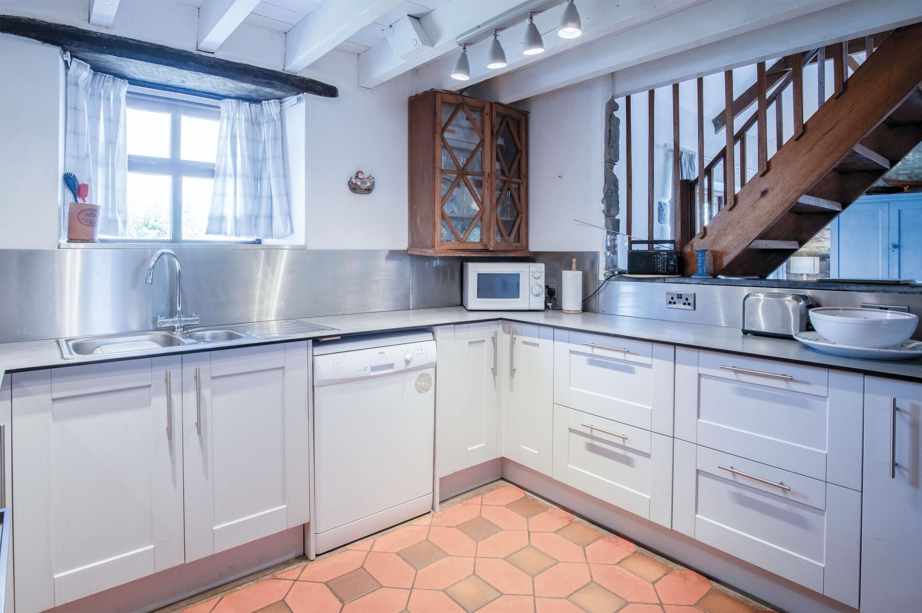 A modern kitchen with white cabinets, a stainless steel sink, a microwave, and a toaster.
