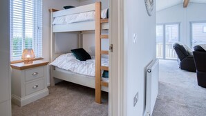 Une chambre avec un lit superposé, un bureau et une chaise, un radiateur et une vue sur l’extérieur.